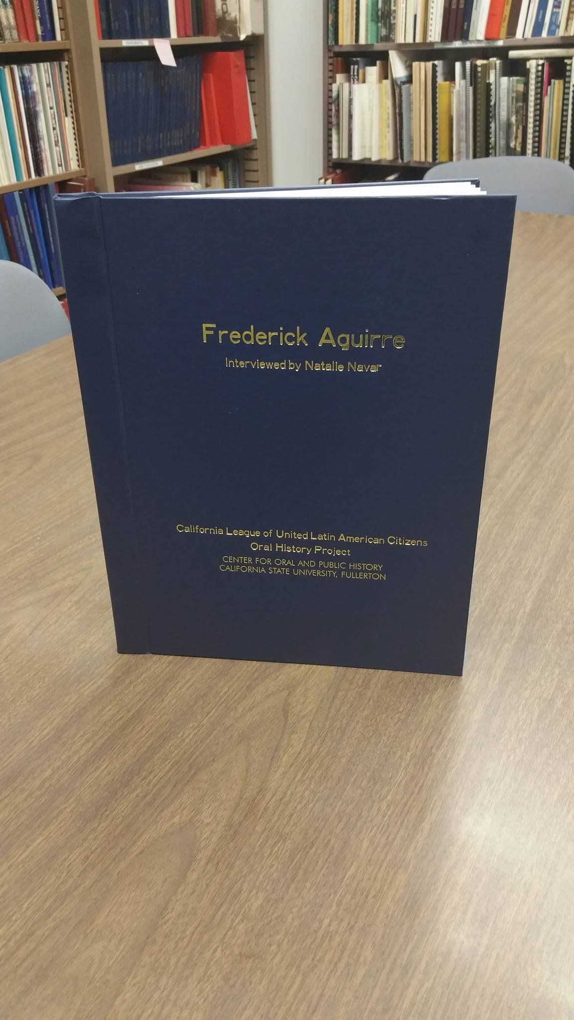 Blue bound book on table with bookshelves in background