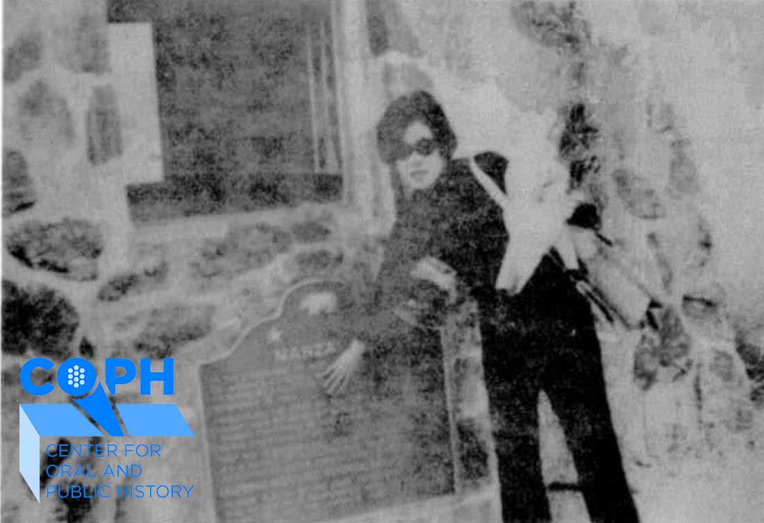 Sue Embrey standing in front of plaque at Manzanar 