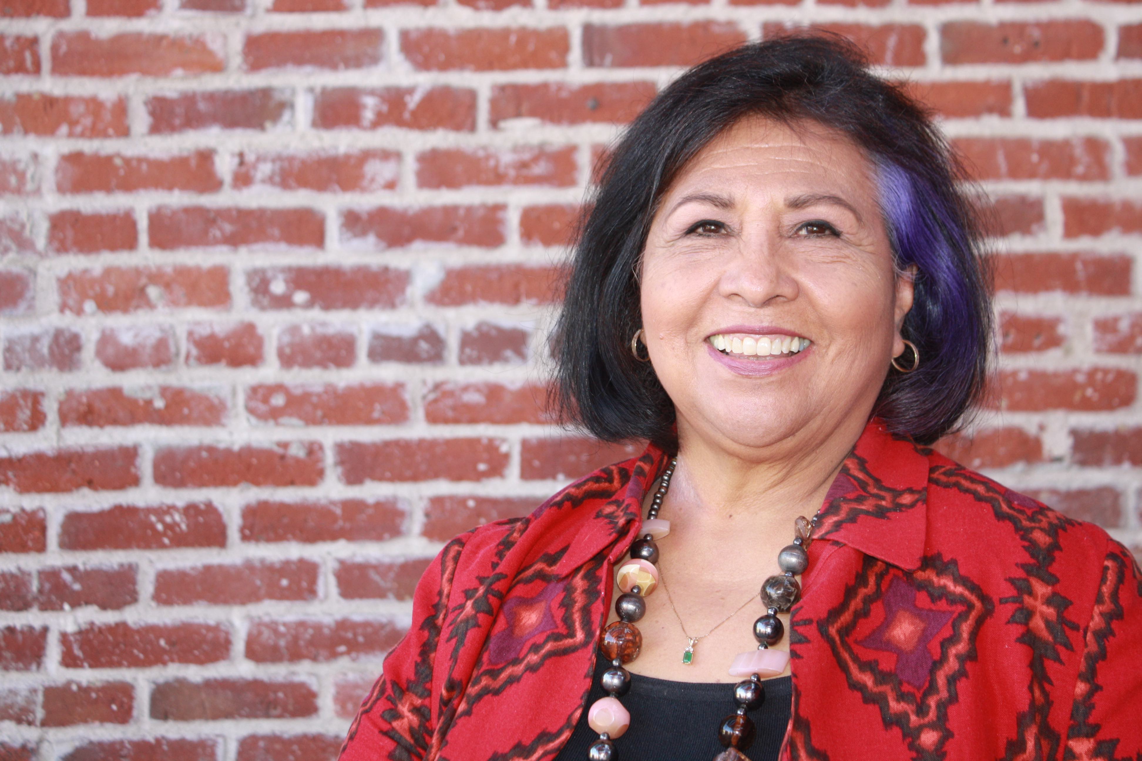 Gloria Molina smiling headshot in front of brick wall