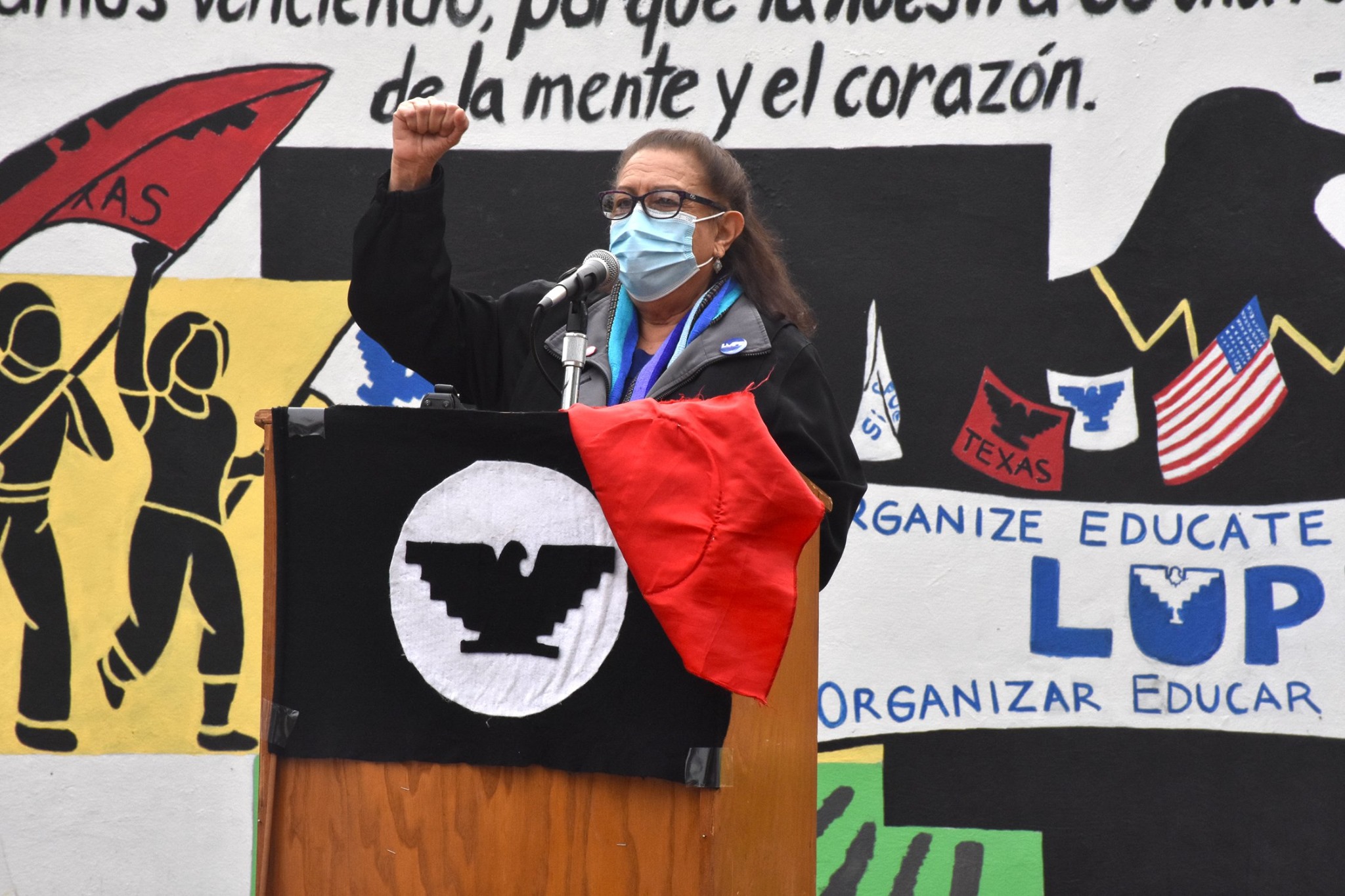 Juanita Valdez-Cox speaking at podium during La Union del Pueblo Entero (LUPE) protest rally