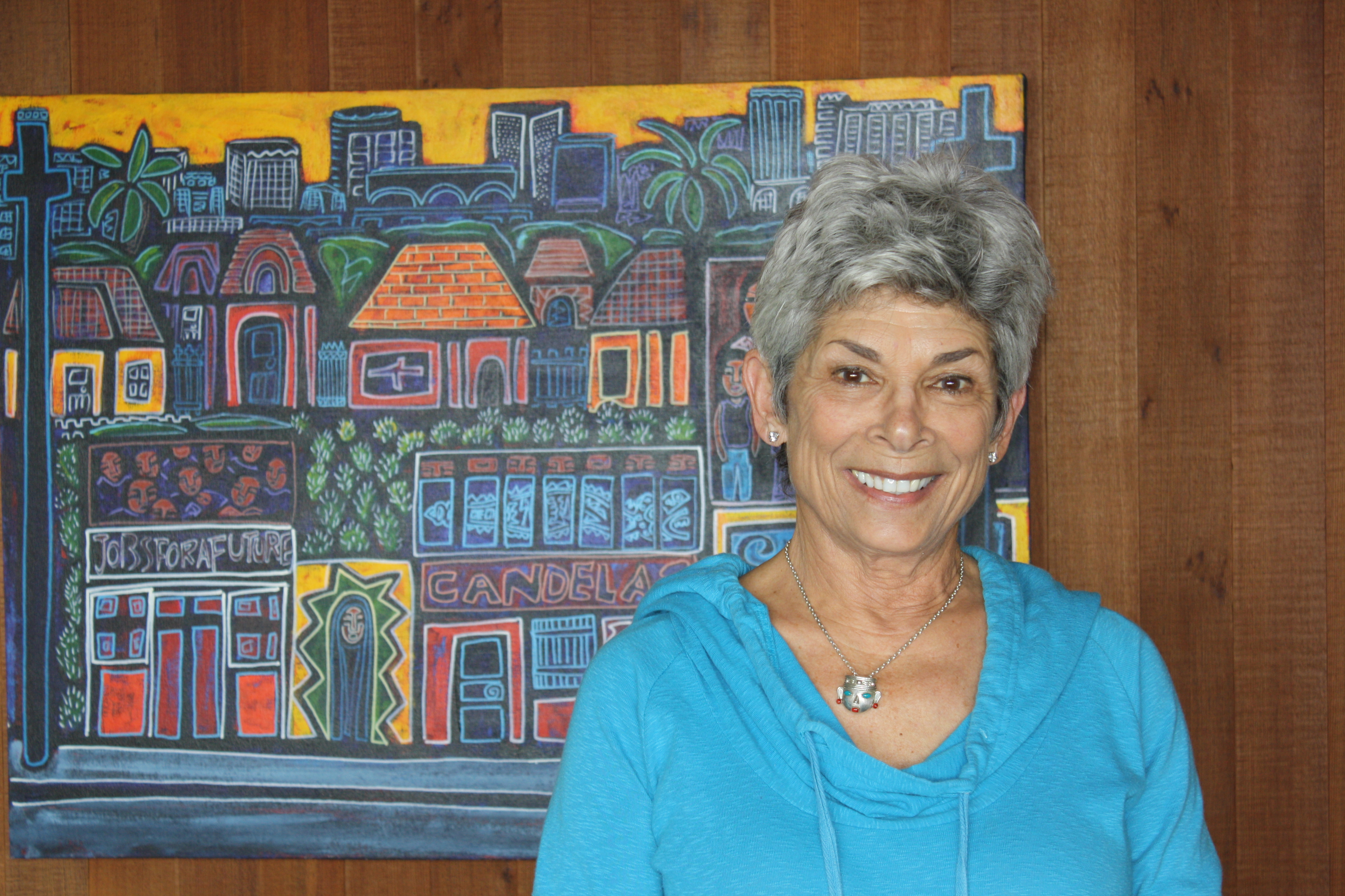 Laura Chick standing in front of painting of houses